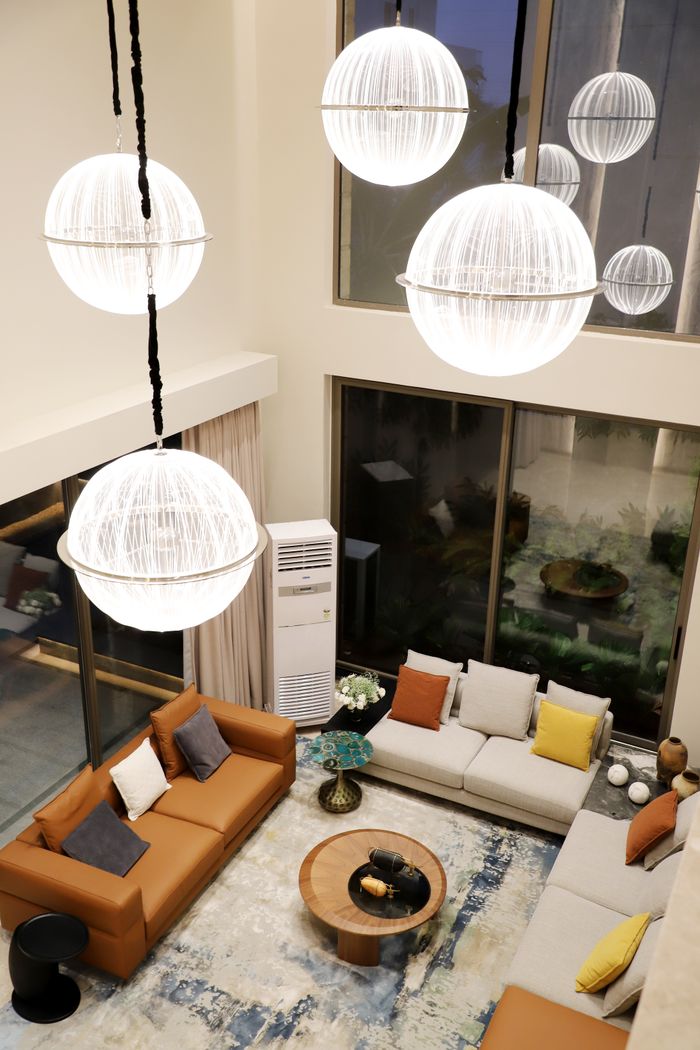 Stylish modern living room featuring large spherical pendant lights, cozy couches, and a coffee table.